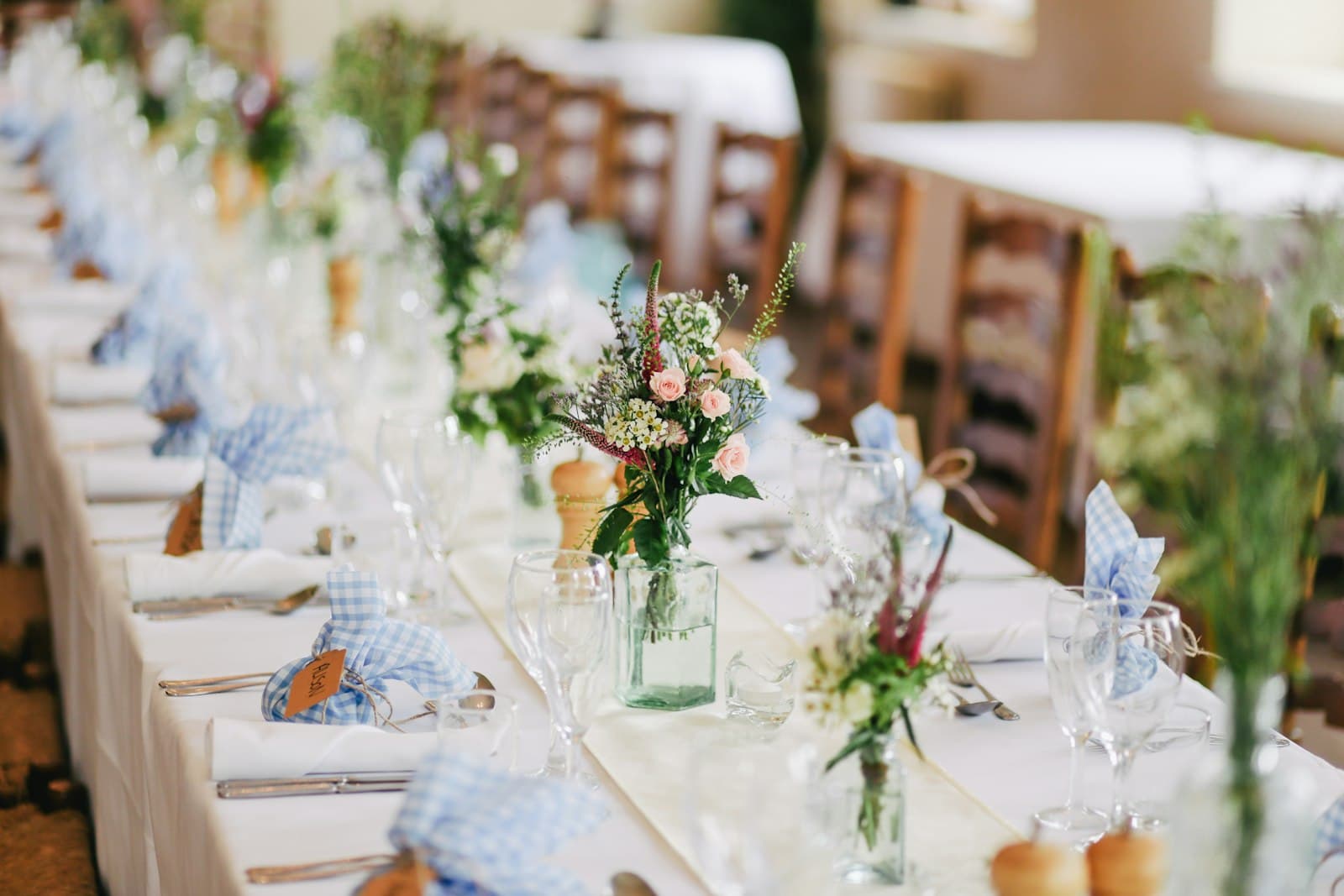 Mesa de casamento posta com louças, taças e arranjos de flores